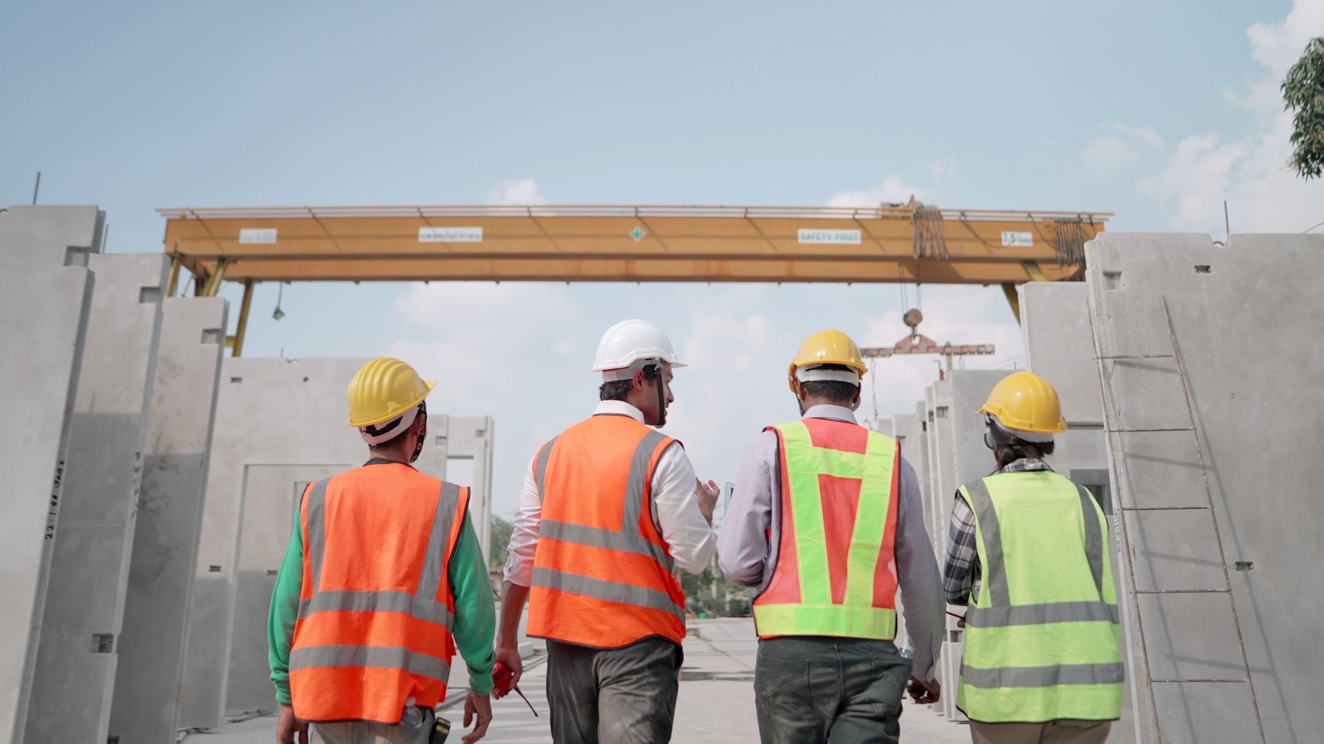 Team of contractor in safety uniform working in real estate business. Professional civil engineer or building architect discussing with foreman about precast wall manufacture of housing estate in factory. Concept of working team, construction industry.