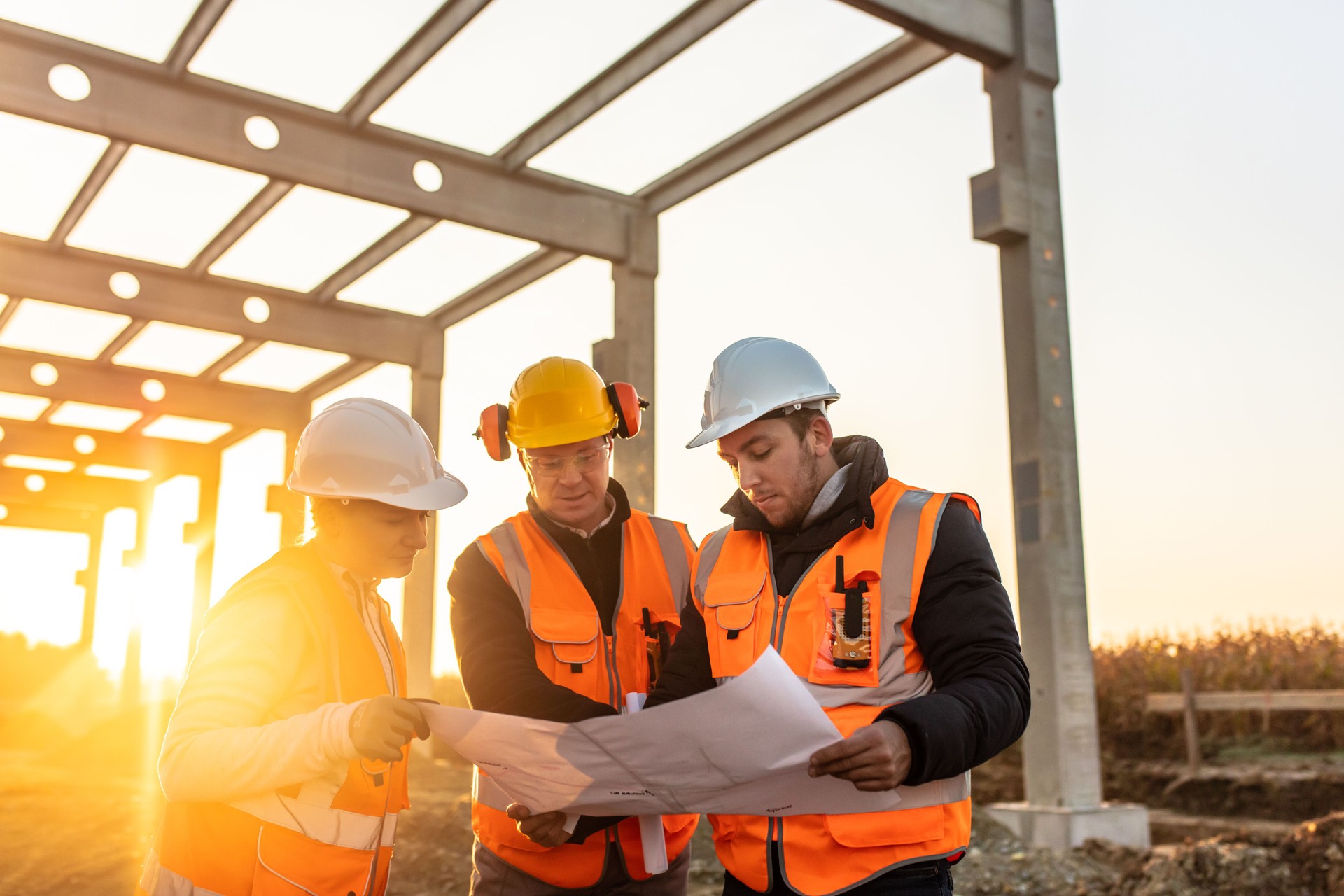 Construction workers analyzing blueprint at site