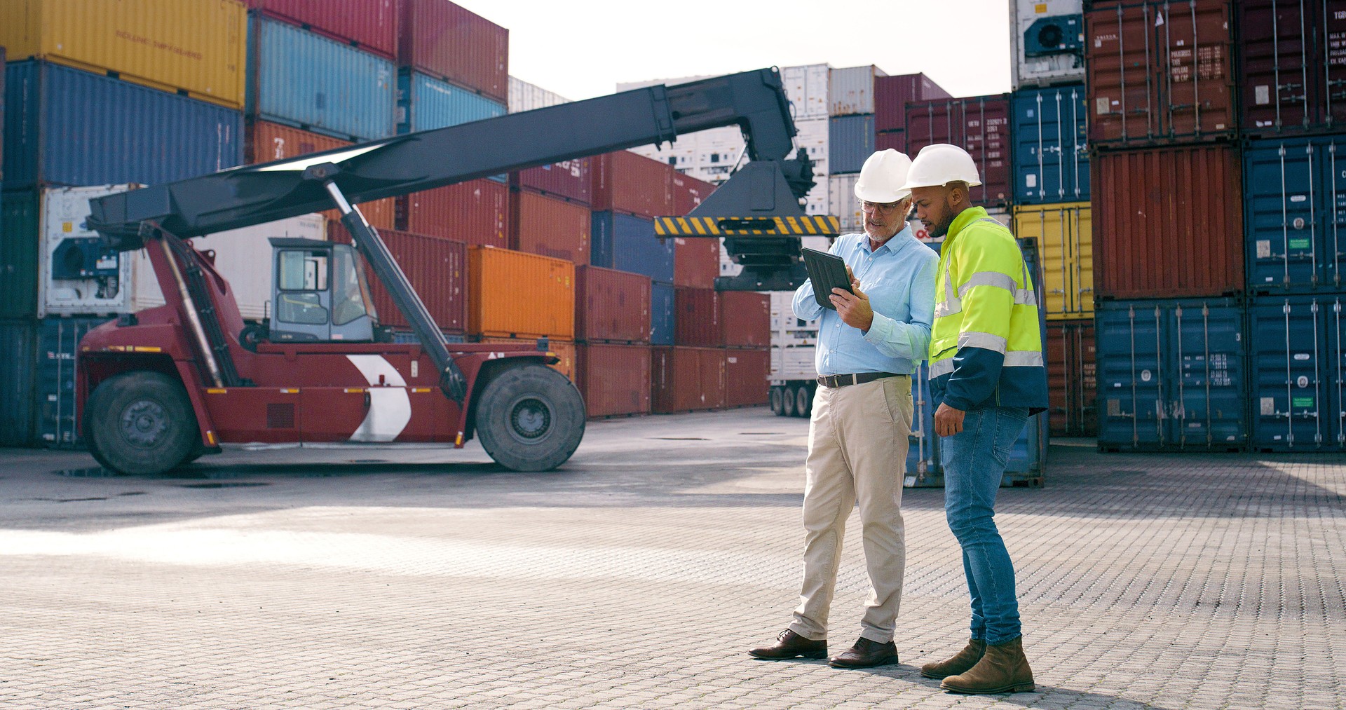 Logistics, man and supervisor in container yard for tablet inventory, stock and supply chain or freight. Discussion, inspection and quality control in industry, shipping in trade for commerce export