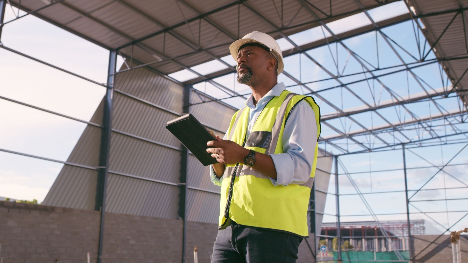 Man, construction and tablet at site for project management, building logistics or app. Male person and engineering worker on digital technology at industrial architecture design